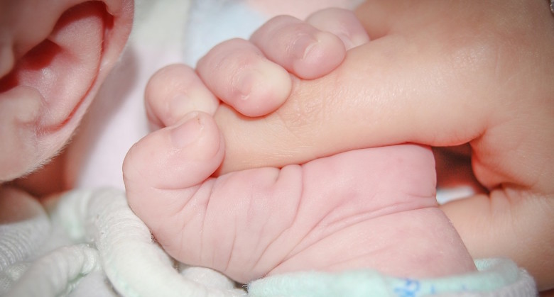 newborn baby holding the hand of a father who just purchased a massachusetts life insurance policy to protect his family.